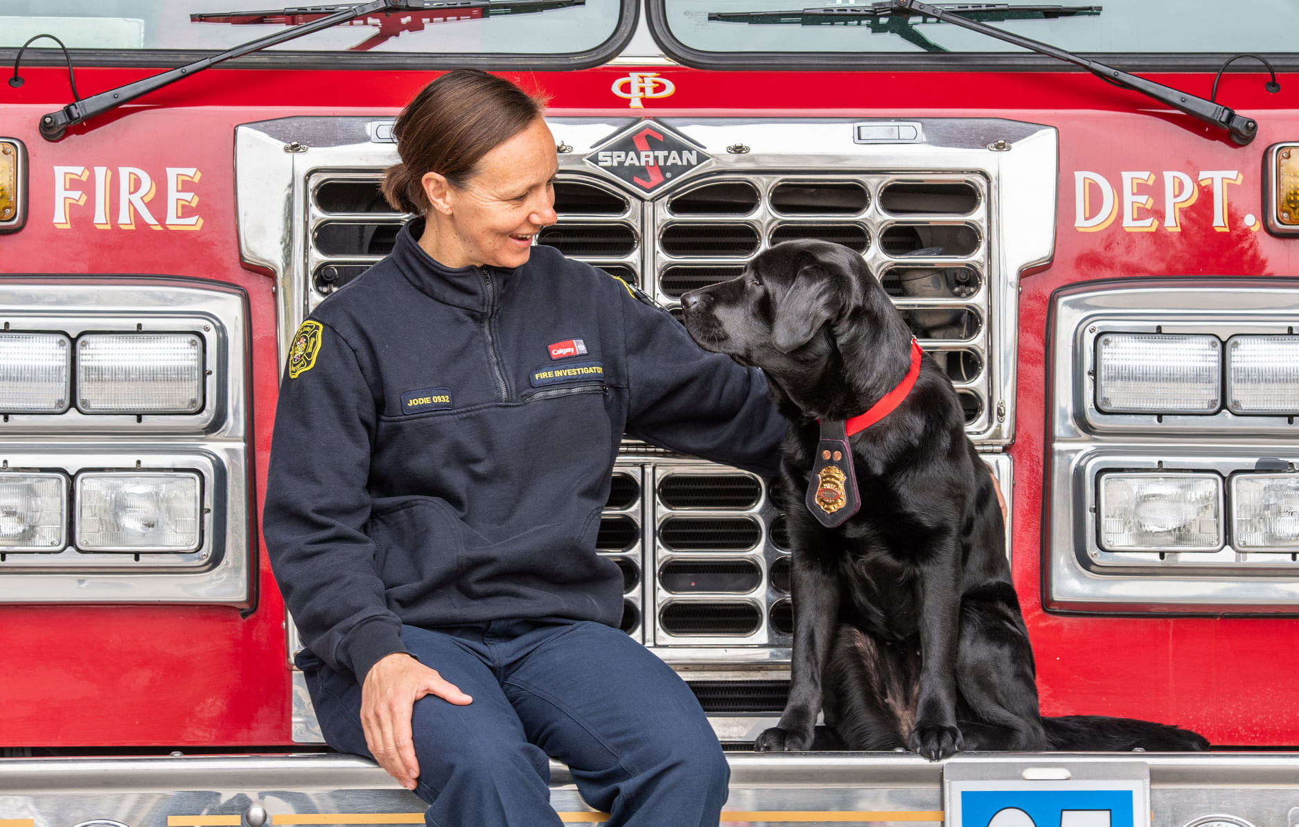 Jodie Grisdale, enquêtrice du service des incendies de Calgary, et Willow, chien détecteur de liquides inflammables, devant un camion de pompiers.